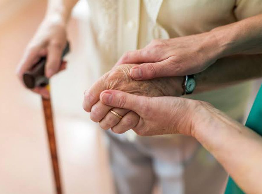 Manos de un adulto mayor acompañado de su cuidadora